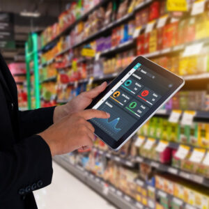 Retail manager using a tablet dashboard in a supermarket aisle